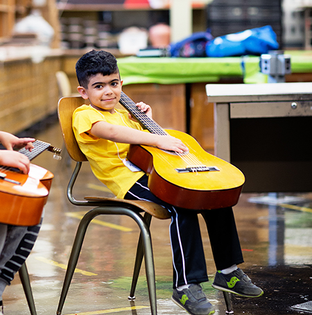 student sitting in chair with guitar