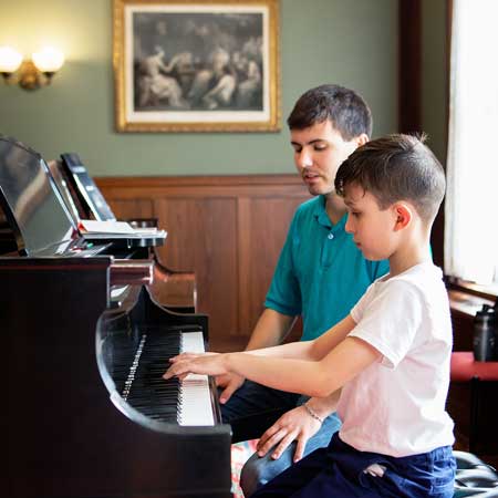 Child and faculty learning at piano