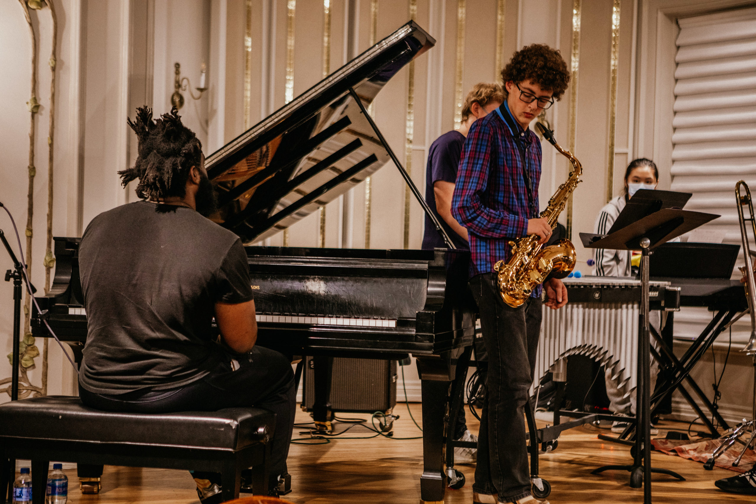 Teen with saxophone plays on stage with an adult man playing piano.